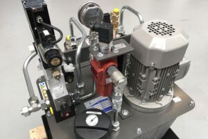 Hydraulikaggregat für Spritzgussmaschine mit Elektromotor, Ventilblock und Manometer.