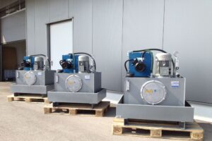 Hydraulikaggregate mit integrierter Kühlung auf Paletten vor Industriehalle.