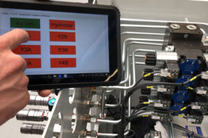 Hydrauliksteuerung mit Tablet und Ventilblock in einer Industrieanlage.