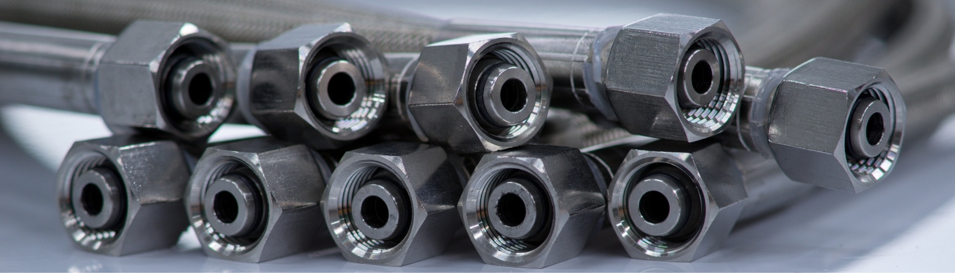 Mehrere Hydraulikschläuche mit metallischen Hochdruckverschraubungen für industrielle Hydraulikanlagen.