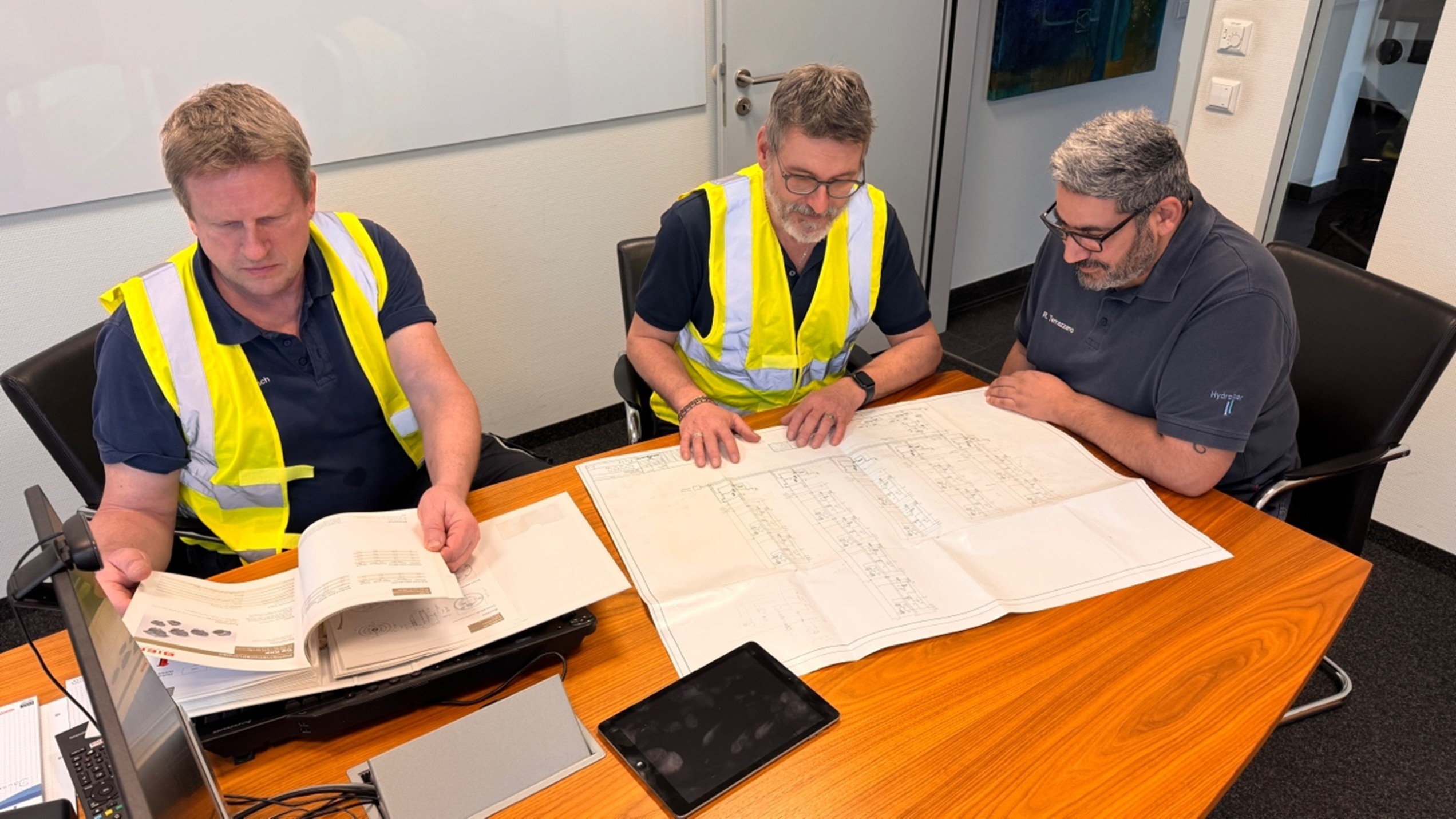 Ingenieure planen ein Hydrauliksystem anhand technischer Zeichnungen und Unterlagen