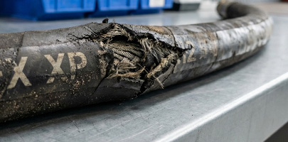 Beschädigter Hydraulikschlauch mit sichtbarem Gewebe und starkem Verschleiß