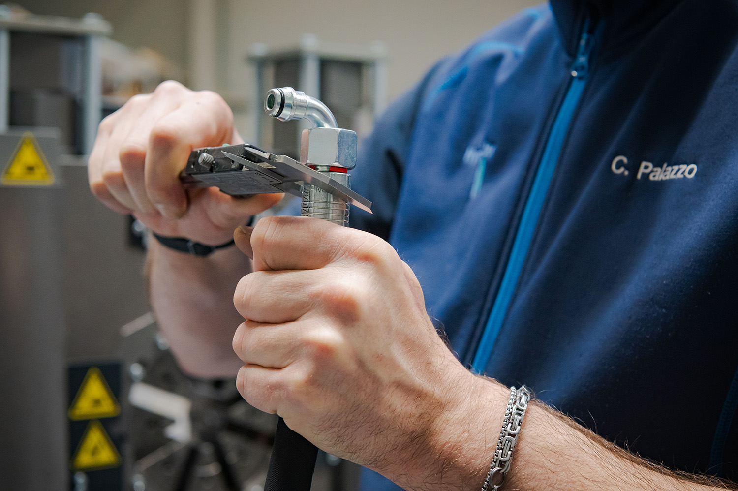 Fachkraft misst Hydraulikarmatur bei Prüfung einer Schlauchleitung